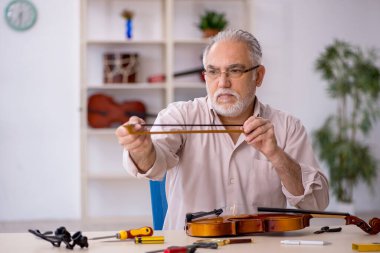 Eski tamirci atölyede müzik aletlerini tamir ediyor.