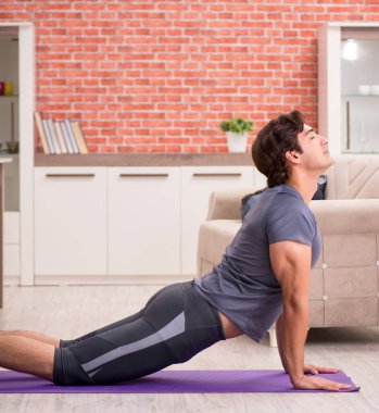 Genç yakışıklı adam evde spor egzersizleri yapıyor.