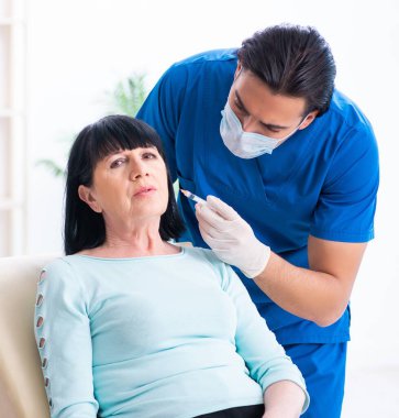 Yaşlı kadın estetik ameliyat için erkek doktoru ziyaret ediyor.