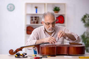 Eski tamirci atölyede müzik aletlerini tamir ediyor.