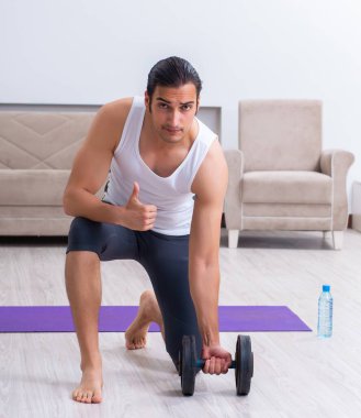 Genç adam evde antrenman ve egzersiz yapıyor.