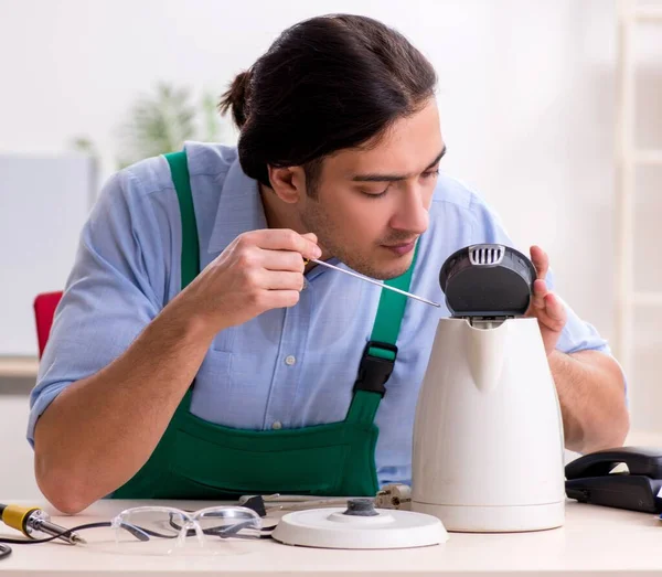 The young man repairing kettle in service centre