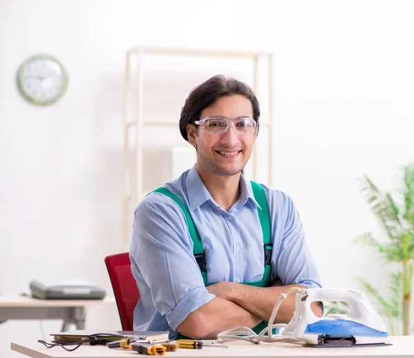 The young man repairing iron in service centre