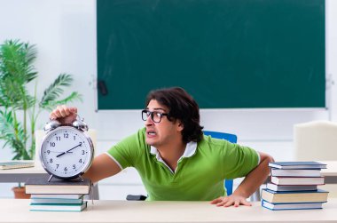 Yeşil panonun önündeki genç erkek öğrenci.