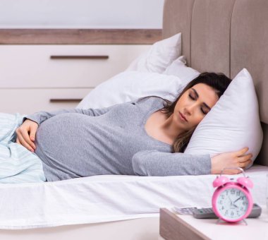 Yatak odasındaki genç hamile kadın.