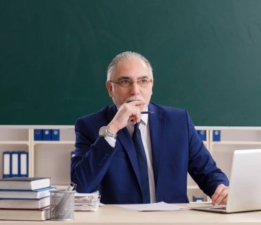 Tahtanın önündeki yaşlı erkek öğretmen.