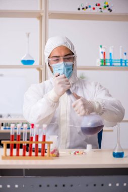 Genç kimyager salgın sırasında laboratuvarda oturuyor.