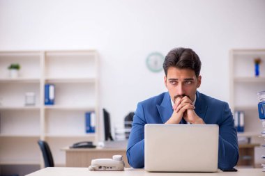 Ofisteki aşırı işten memnun olmayan genç bir erkek işçi.