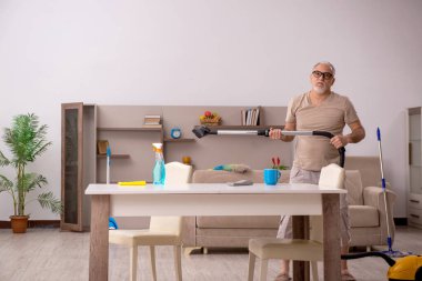 Evde ev işi yapan yaşlı bir adam.