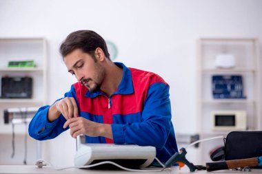 Genç tamirci atölyede ısıtıcıyı tamir ediyor.