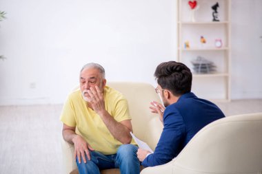 Yaşlı adam genç psikoterapisti ziyaret ediyor.