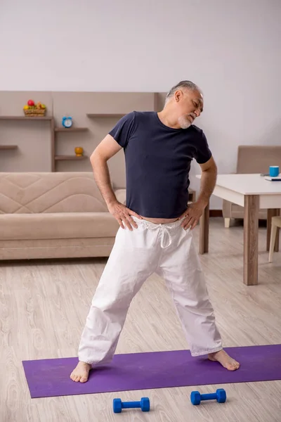 Old man doing sport exercises indoors