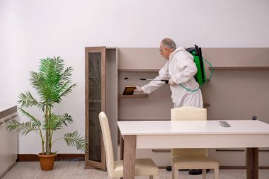 Yaşlı müteahhit evde haşere kontrolü yapıyor.