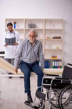 Tekerlekli sandalyedeki yaşlı adam genç doktor radyoloğu ziyaret ediyor.