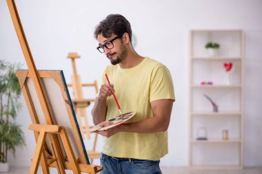 Genç erkek ressam evde resim yapmaktan hoşlanıyor.