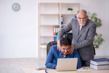 Eski patron ve genç çalışan işyerinde çalışıyor.