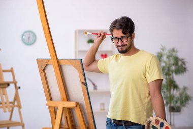 Genç erkek ressam evde resim yapmaktan hoşlanıyor.