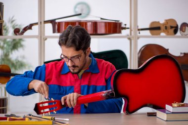 İçeride müzik aletlerini tamir eden genç bir adam.
