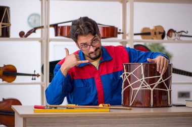 İçeride müzik aletlerini tamir eden genç bir adam.