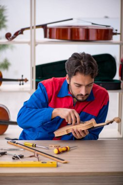 İçeride müzik aletlerini tamir eden genç bir adam.