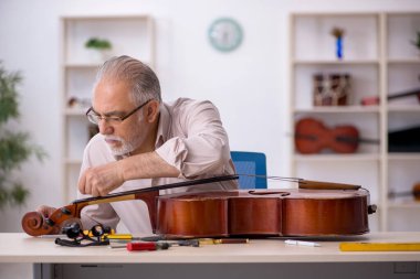 Eski tamirci atölyede müzik aletlerini tamir ediyor.