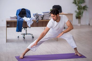 Genç işadamı işyerinde spor egzersizleri yapıyor.