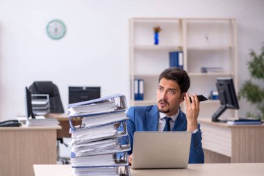 Ofisteki aşırı işten memnun olmayan genç bir erkek işçi.