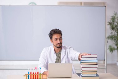 Genç kimyacı öğretmen beyaz tahtanın önünde.