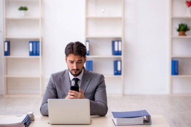 Genç işadamı işyerinde oturuyor.