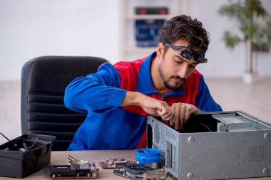 Atölyede bilgisayar tamir eden genç bir tamirci.