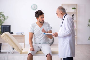 Genç hasta yaşlı erkek doktoru ziyaret ediyor.