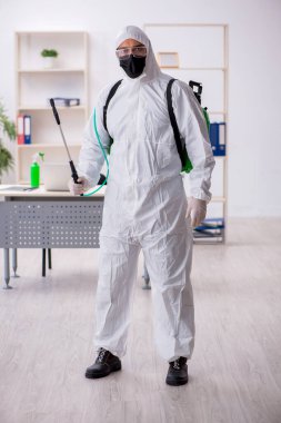 Young contractor disinfecting office during pandemic