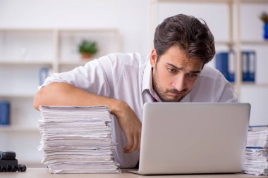 Genç işadamı ve işyerinde çok fazla iş var.