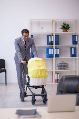 Genç işadamı işyerinde yeni doğan çocuğa bakıyor.