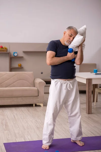 Old man doing sport exercises indoors