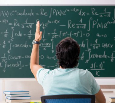 Tahtanın önündeki genç erkek matematikçi.