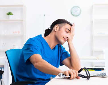 Klinikte çalışan genç erkek doktor.