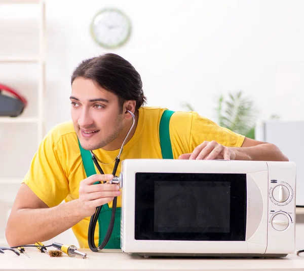 The young repairman repairing microwave in service centre