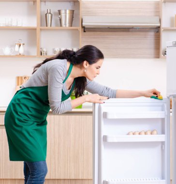 Hijyen konseptiyle buzdolabını temizleyen genç kadın.