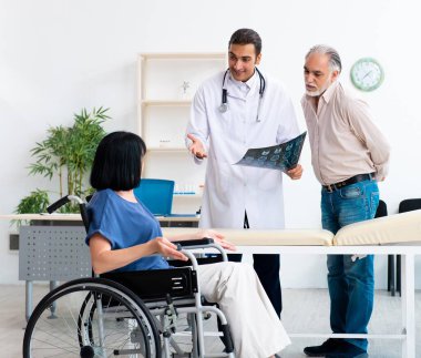 Yaşlı çift genç erkek doktoru ziyaret ediyor.