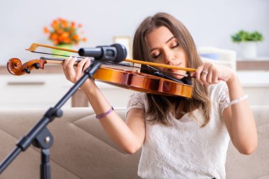 The female beautiful musician playing violin at home