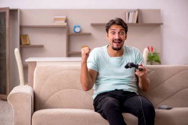 Evde oyun oynayan genç bir erkek öğrenci.