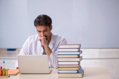 Genç kimyacı öğretmen beyaz tahtanın önünde.