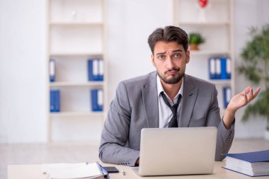 Genç işadamı işyerinde oturuyor.