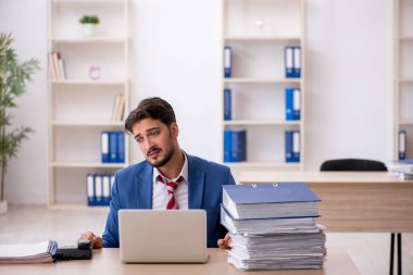 Genç işadamı ve işyerinde çok fazla iş var.