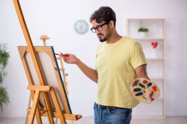 Genç erkek ressam evde resim yapmaktan hoşlanıyor.