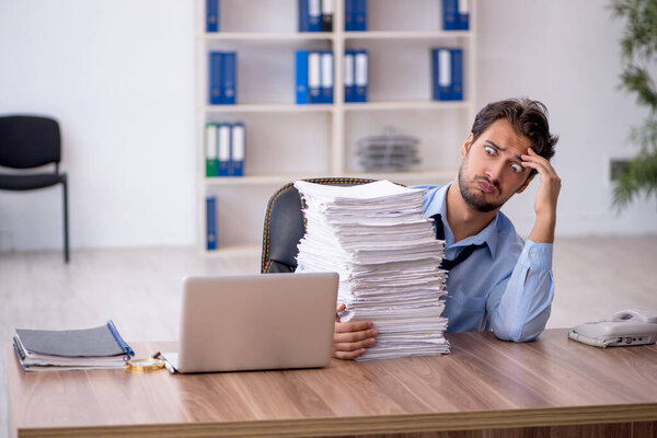 Молодой бизнесмен и слишком много работы в офисе