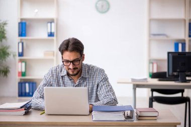 Genç erkek çalışan işyerinde oturuyor.