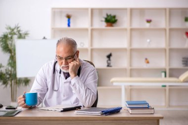 Klinikte çalışan yaşlı bir doktor.