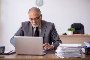 Eski erkek patron iş yerinde oturuyor.